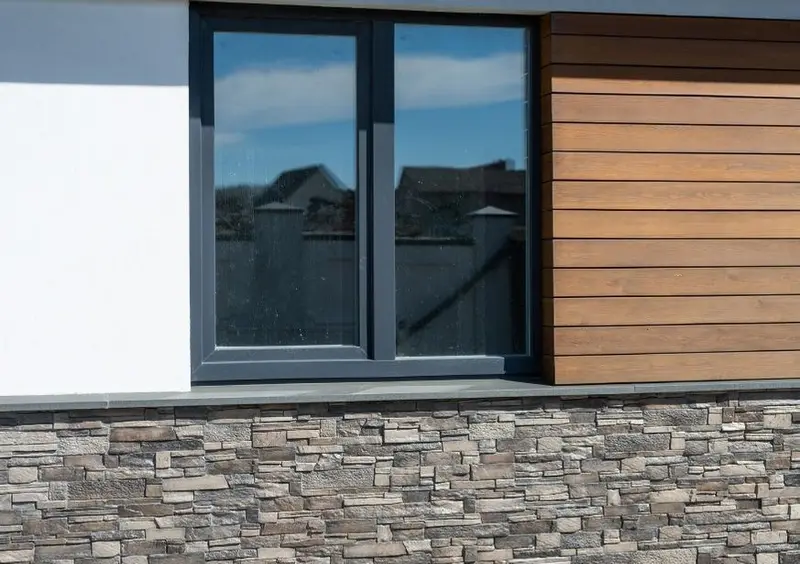Modern house exterior with stone cladding and timber panelling below a window