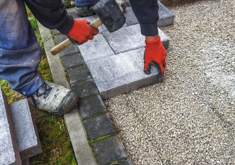 Paving bricks being laid and tapped into place on a compacted gravel base