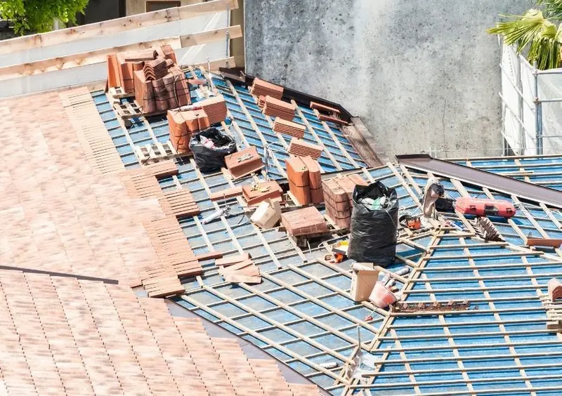 Roof being re-tiled, with old tiles stacked on exposed battens and underlay